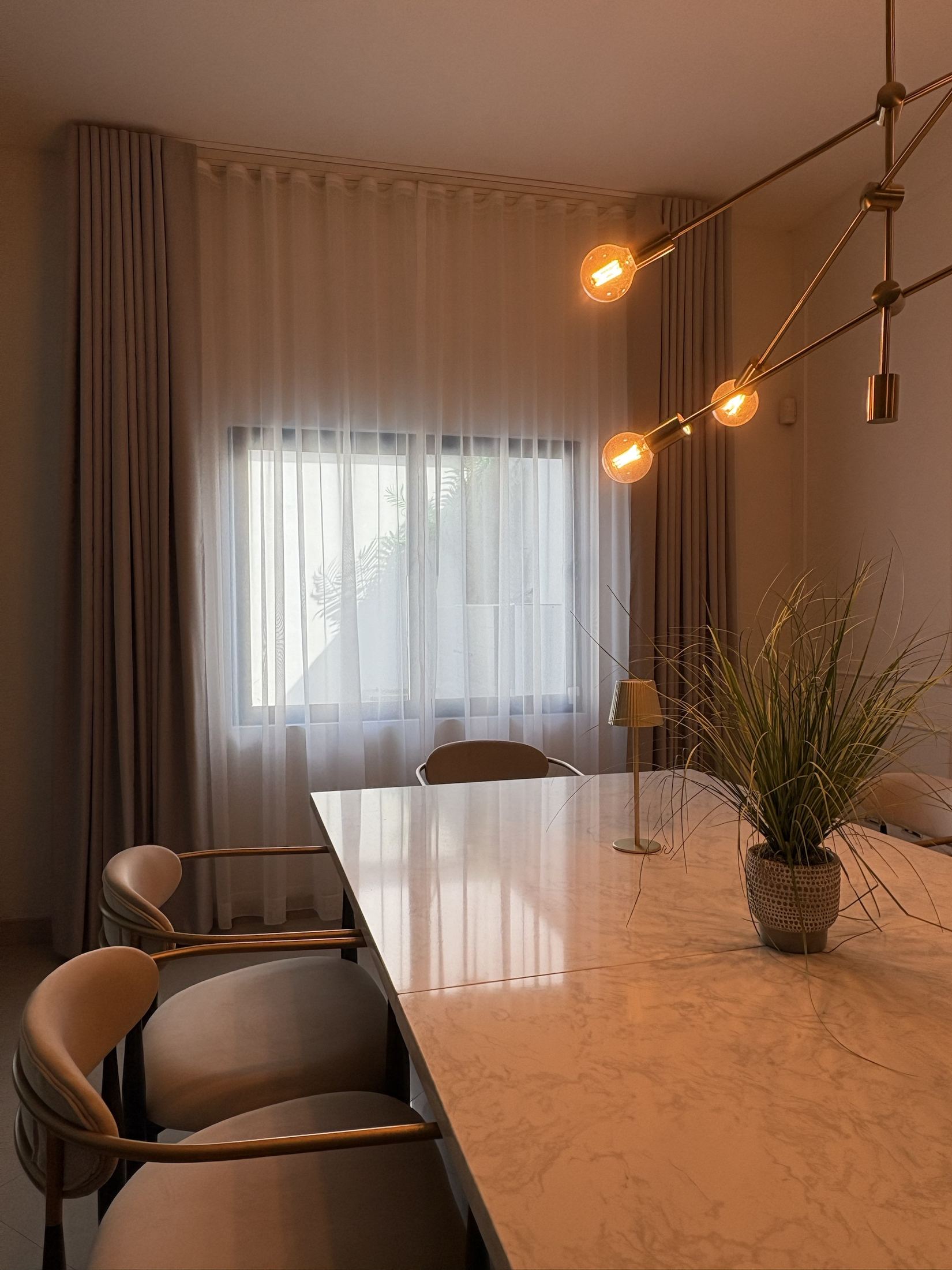 Comedor con cortinas de onda y lámpara dorada