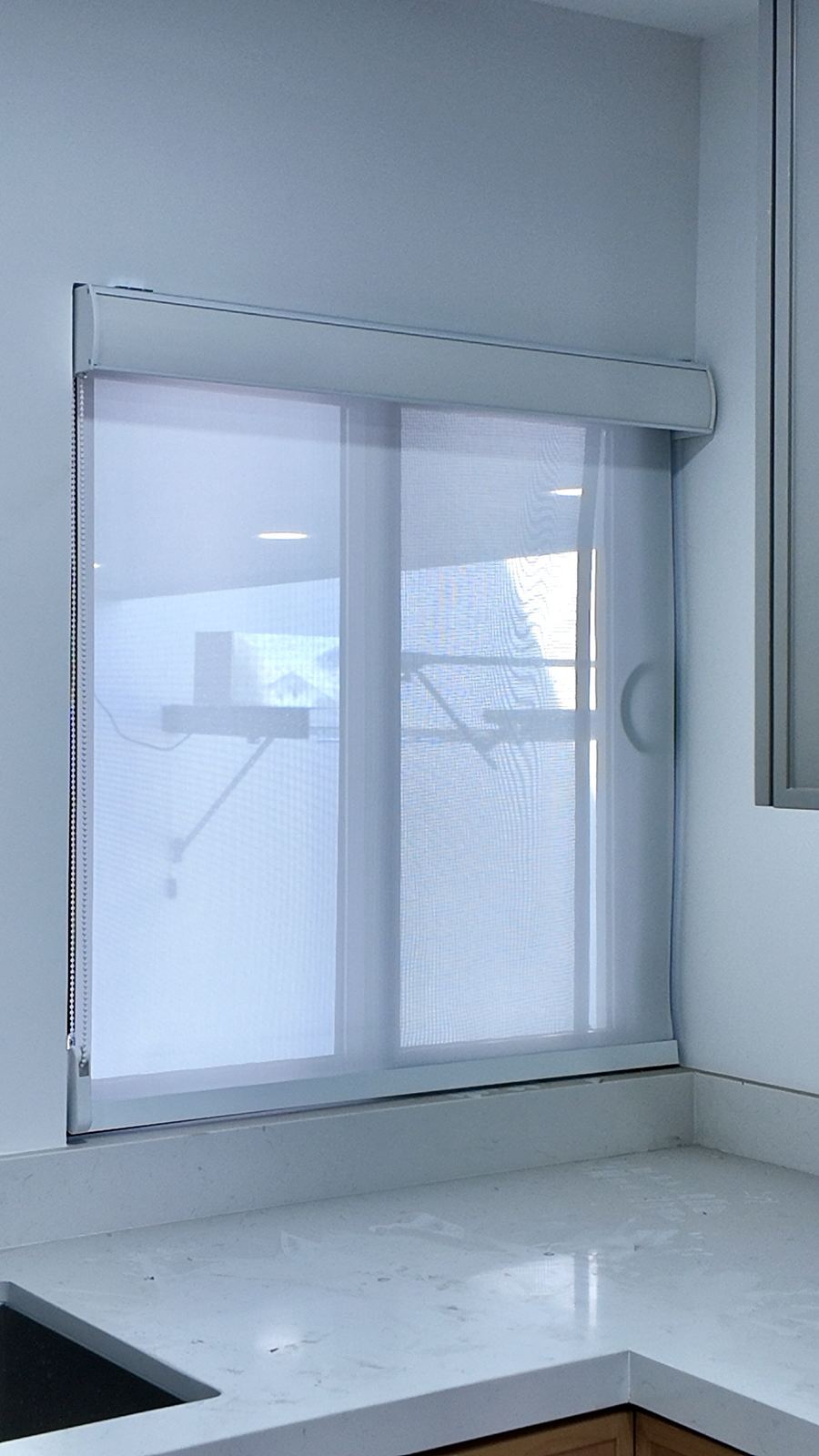 Persiana screen blanca en una ventana de cocina